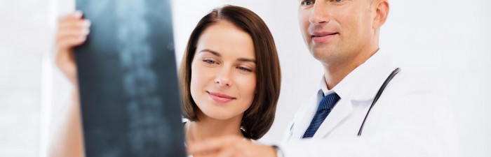 Medical professionals looking at x-ray of spine.